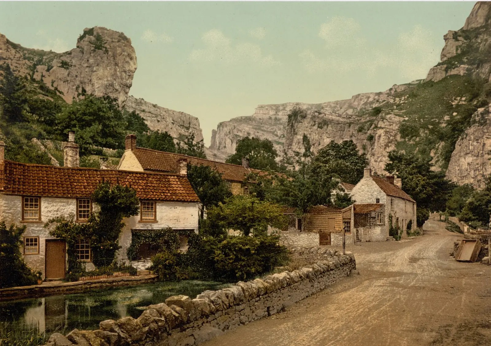 Cheddar village under Lion Rock, Somerset, around 1895: cottages, a stone wall and a dirt road